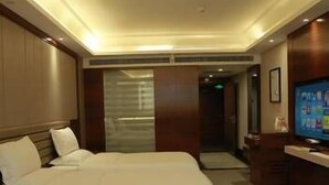 Een hotelkamer met een groot bed, een televisie en een bureau.
