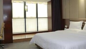 Een hotelkamer met een groot bed, een raam met zonwering en een stoel.