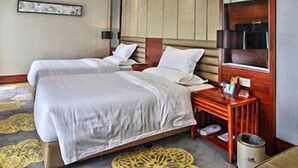 Een hotelkamer met een groot bed, een nachtkastje, een spiegel en een vloerkleed met een geometrisch patroon.