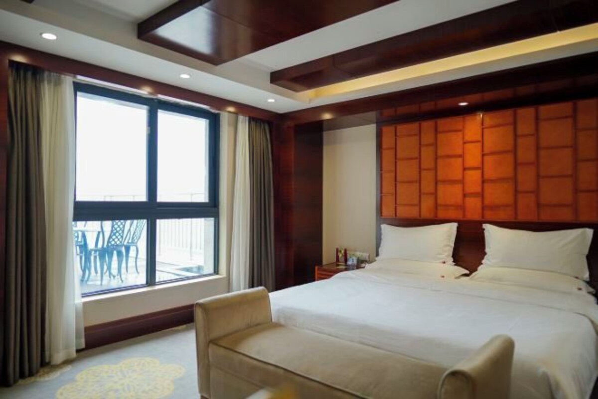 Una camera d'hotel con un letto grande, una zona salotto e vista sull'esterno.
