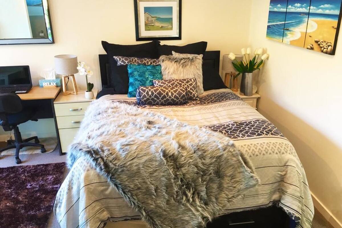 A neatly arranged bedroom with a bed, a desk, and a chair.