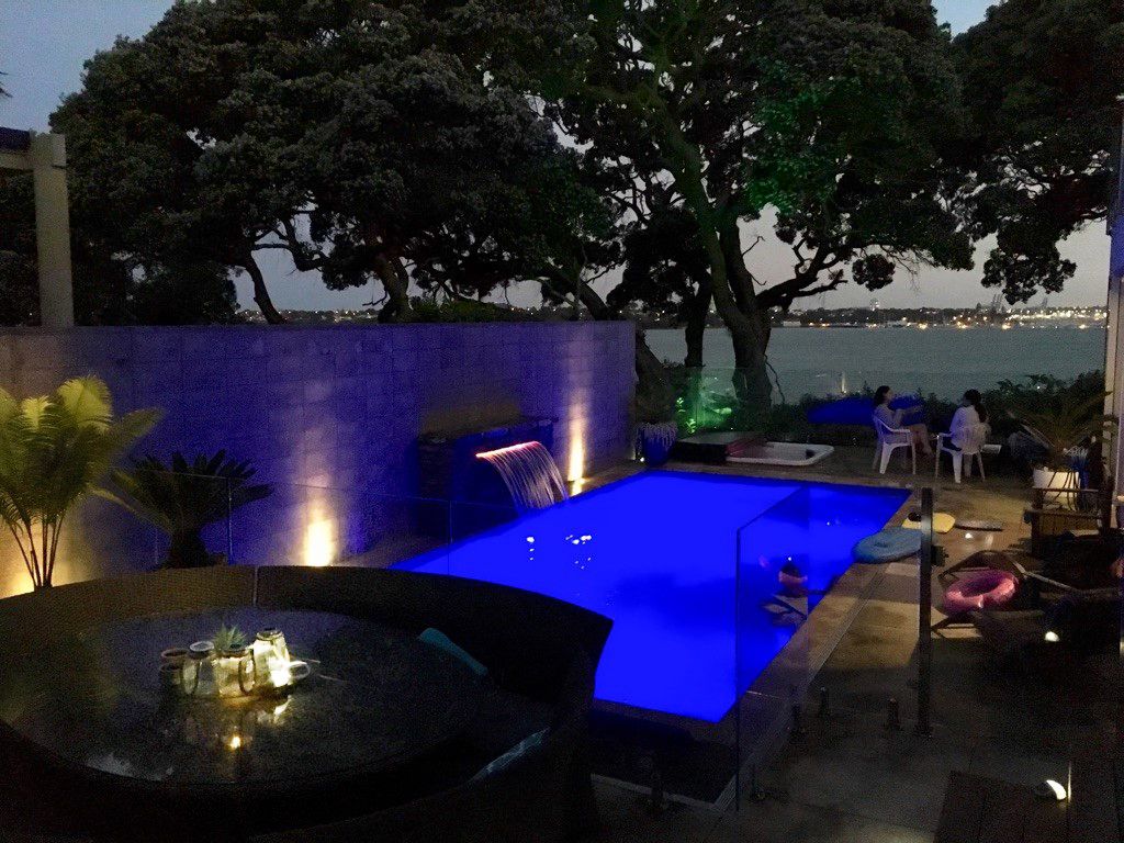 Un espace piscine extérieur avec vue sur la mer, agrémenté de chaises longues et d’une table où sont servis des boissons.