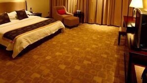 A hotel room with a large bed, a chair, a desk, and a TV. - Yingjia Resort (Lu'an)
