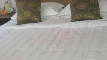 A bed with white bedding and two decorative pillows with a patterned design.
