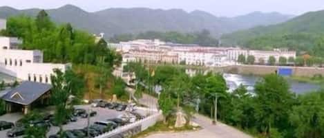 A parking lot with several cars, a building with a flat roof, and a river in the background.