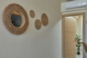 A wall with a large woven mirror and three smaller woven wall hangings.