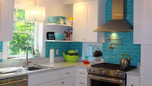 A kitchen with white cabinets, a stainless steel stove, and a window with a view of greenery. - Charming cottage apartment, private, quiet and sparkling clean.  1 bedrm 1 bath. (Kennebunk)