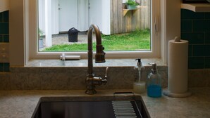 A kitchen with a sink, faucet, and a window overlooking a backyard. - Charming cottage apartment, private, quiet and sparkling clean.  1 bedrm 1 bath. (Kennebunk)