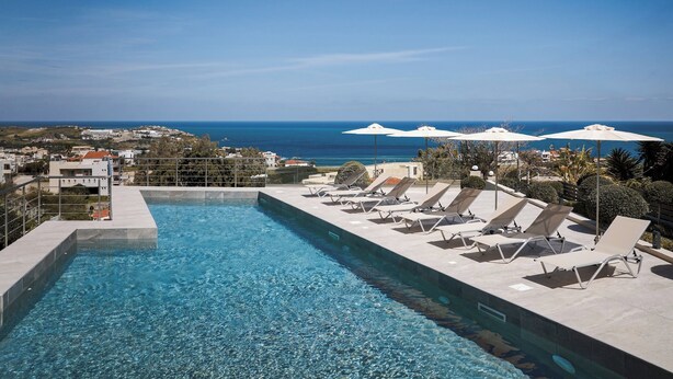 Une piscine dotée de chaises longues et de parasols, offrant une vue sur la côte.
