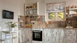 Een keuken met een fornuis, oven, witte kasten, een betegelde spatwand en een raam.