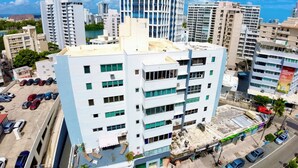 A multi-story hotel with a rooftop pool area, surrounded by high-rise buildings and a busy street. - Modern 2BR Apartment Steps from La Concha & the Beach – Prime Condado (Santurce)