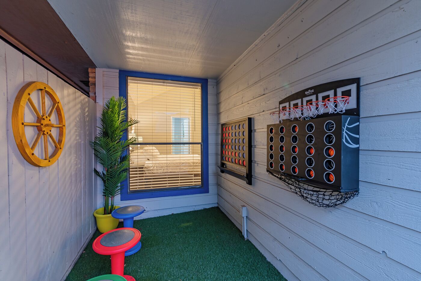 A small, enclosed space with a basketball hoop, a dartboard, and a wheel of fortune game.