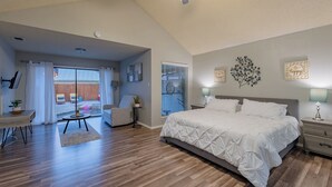 Un dormitorio con una cama grande, un ventilador de techo, un escritorio y vistas al patio trasero a través de una puerta corredera.