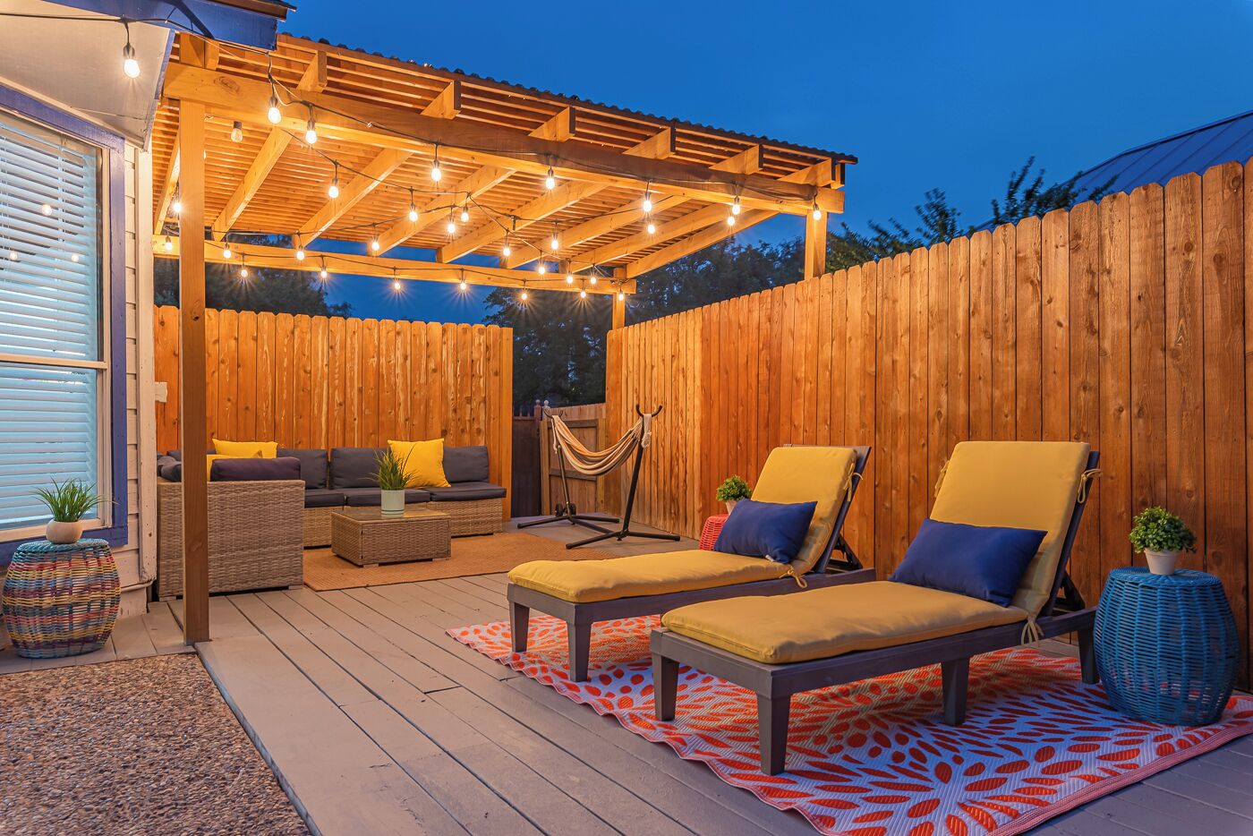 An outdoor patio with wooden furniture, string lights, and a hammock.