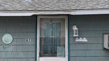 A house with a white door, number 82, and a small porch area with a lantern and potted plants.