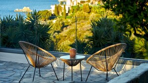 A balcony with two wicker chairs and a table, overlooking a coastal landscape with a house in the background. - "Villa Caress" - Spacious villa with private pool and sea view (Malevizi)