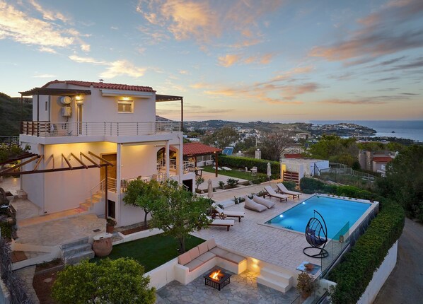 Une maison moderne à deux étages, dotée d’une piscine, d’un espace extérieur aménagé et offrant une vue sur la mer.