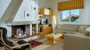 A modern living room with a fireplace, a sofa, a television, and a window with curtains. - "Villa Caress" - Spacious villa with private pool and sea view (Malevizi)