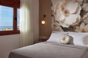 A bedroom with a bed, a nightstand, a wall-mounted light, and a window with curtains.