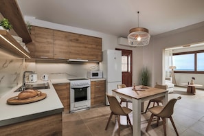 Une cuisine moderne avec des meubles en bois, un four encastré, un four à micro-ondes et un coin repas comprenant une table et des chaises.