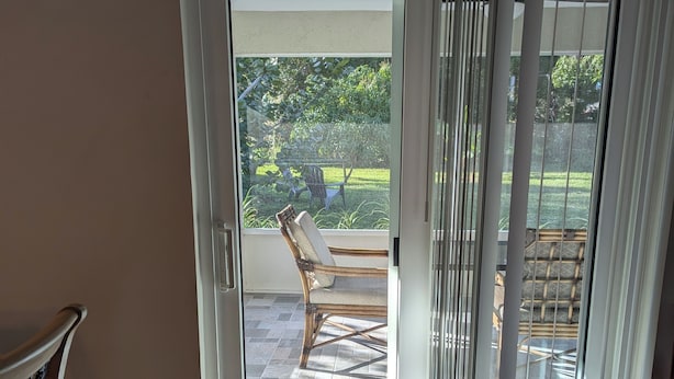 Ein Zimmer mit einer Schiebetür aus Glas, die auf eine Terrasse im Freien führt.