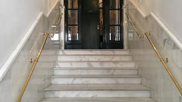A marble staircase with gold handrails leading to a dark door with glass panels.