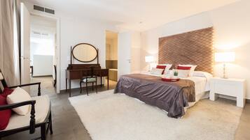 A modern bedroom with a bed, bedside tables, a desk, and a chair.