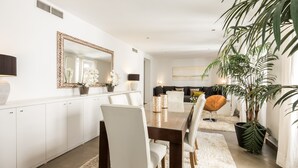 Un espace repas moderne avec une table en bois et des chaises blanches, un grand miroir et une plante en pot.