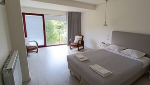 A bedroom with a large bed, a chair, a nightstand, and a window with curtains. - Villa with private pool near Gerês (Terras de Bouro)