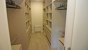 A narrow walk-through closet with multiple shelves and hanging spaces, a radiator on the floor, and a white door at the end. - Villa with private pool near Gerês (Terras de Bouro)