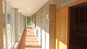 A corridor with stone walls, wooden doors, and large windows. - Villa with private pool near Gerês (Terras de Bouro)