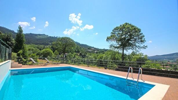 A rectangular swimming pool with a metal ladder, surrounded by a wooden deck. - Villa with private pool near Gerês (Terras de Bouro)