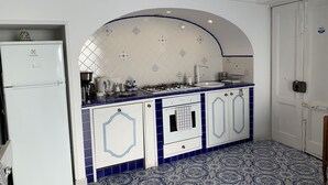 A kitchen with white cabinets, a white refrigerator, a stove, and a sink. - Casa Rosetta: A terrace on the sea paradise of the Amalfi Coast (Praiano)