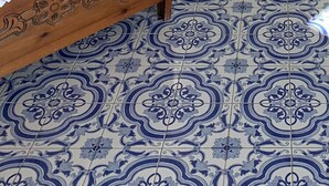 A room with a wooden bed, a blue and white patterned floor, a small table with a sewing machine, and a wall-mounted candelabra. - Casa Rosetta: A terrace on the sea paradise of the Amalfi Coast (Praiano)
