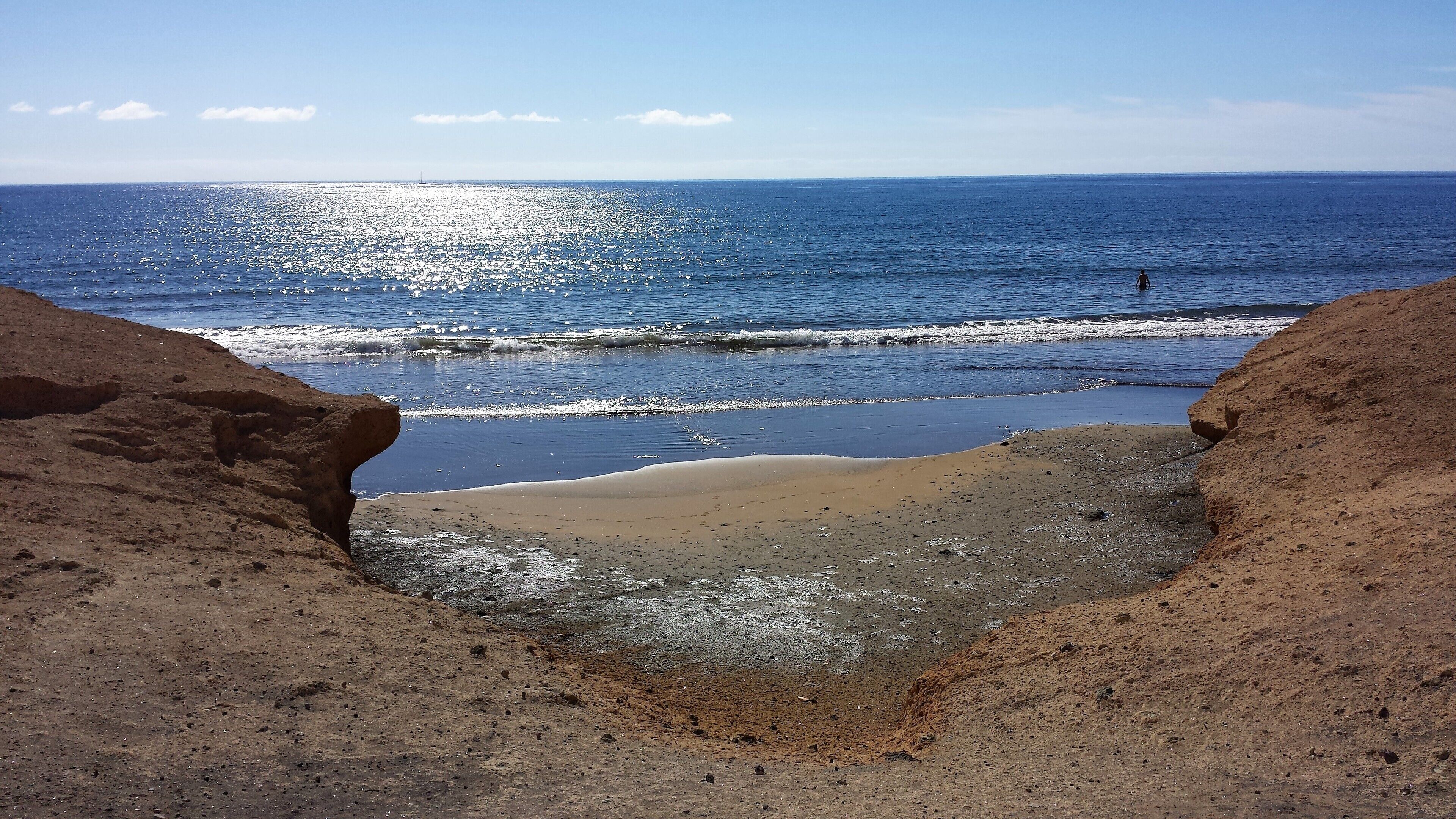 Un paisaje costero con una playa arenosa, acantilados rocosos y el océano.