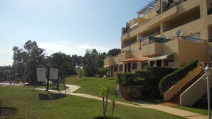 Un edificio de varios pisos con balcones, un patio central y una pequeña palmera.