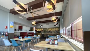 A modern restaurant with wooden tables and chairs, a bar area, and a view of the city through large windows. - Manilva Andalusië, Spain (Manilva)