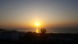 Un coucher de soleil sur une zone côtière, avec des bâtiments au premier plan.
