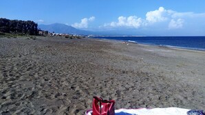 A beach with a red bag on the sand, a clear sky, and distant mountains. - Manilva Andalusië, Spain (Manilva)