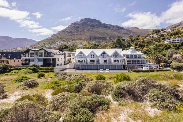 A modern hotel with a large, multi-story structure, a prominent balcony, and a view of a mountain. - Cape Town Townhouse. Panoramic Sea & Mountain Views. Beach 50m. Spectacular! (Cape Town)