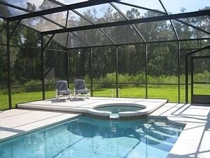 A swimming pool with two lounge chairs and a hot tub, enclosed by a glass structure. - Villa with Private Pool and Spa (Kissimmee)
