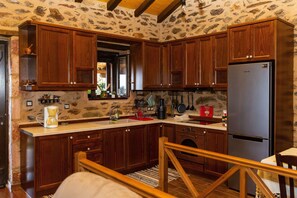 Compact kitchen with oven and refrigerator, dining area with wooden table and chairs, and a window with a view.