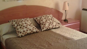 A bedroom with a wooden bed, two patterned pillows, a bedside lamp, and a nightstand. - "EL TRASTERO" Penthouse, cozy, bright and quiet (Santa Marta de Tormes)