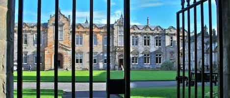 Stately historic building with a symmetrical facade and ornate entrance, set amidst a well-manicured lawn.