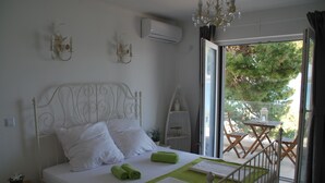 Een slaapkamer met een metalen bedframe, wit beddengoed, een groene handdoek en uitzicht op het omliggende landschap door een glazen deur.
