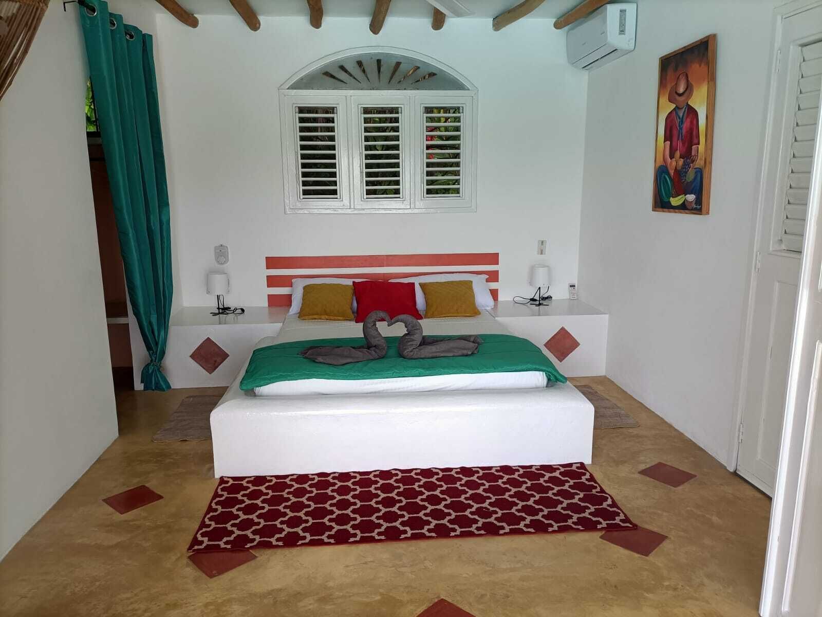 Ein Schlafzimmer mit Bett, Fenster, einem Gemälde und einer Tür.