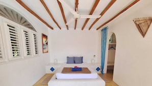 Ein Schlafzimmer mit Bett, Deckenventilator und Fenster mit Rollläden.