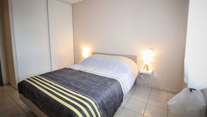 Un dormitorio con cama, lámparas de noche y un armario.