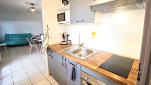 Una cocina compacta equipada con microondas, cafetera y una moderna placa de inducción.