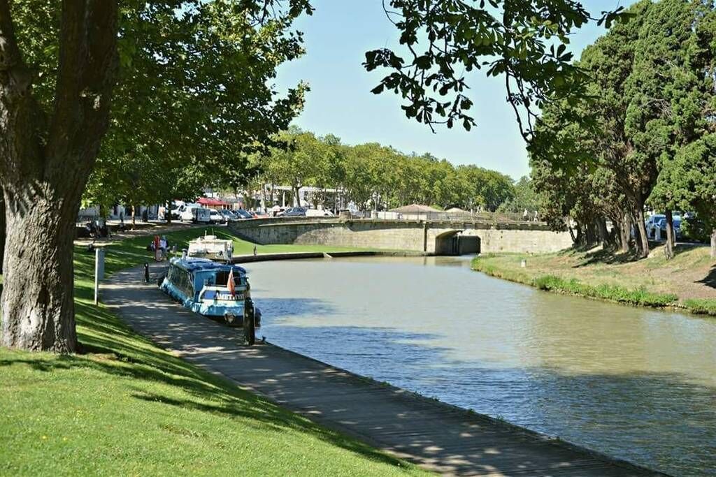 Un canal avec des bateaux, un pont et des arbres.